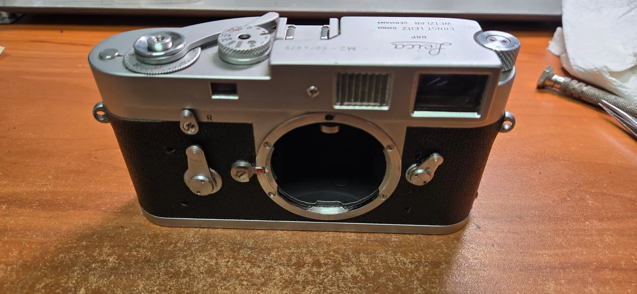 Leica M2 front after full CLA and leather skin replacement, showing the reassembled silver top cover and textured black covering around the lens mount.