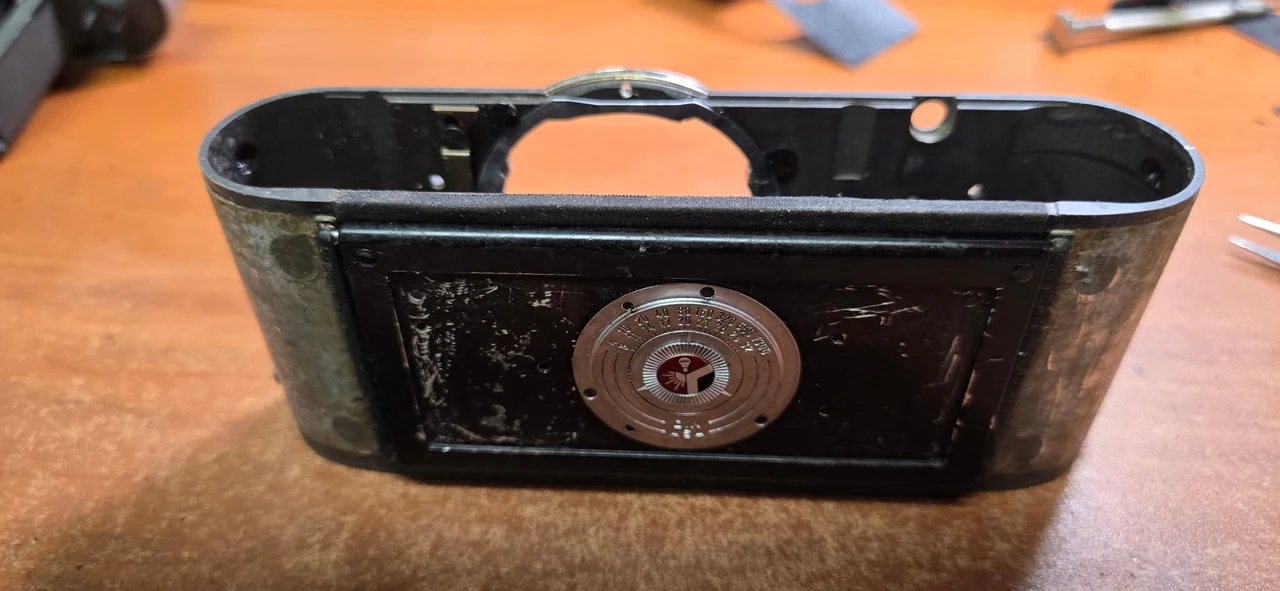 Leica M2 rear before repair, showing an open body shell, bare side surfaces and a patchy rear covering around the circular film reminder dial.